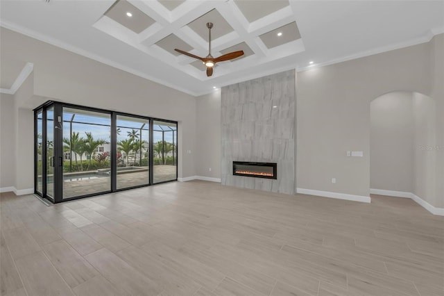 unfurnished living room with crown molding, a high ceiling, coffered ceiling, a fireplace, and beamed ceiling