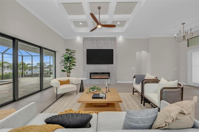 living room with a tile fireplace, coffered ceiling, light hardwood / wood-style floors, ceiling fan with notable chandelier, and beamed ceiling