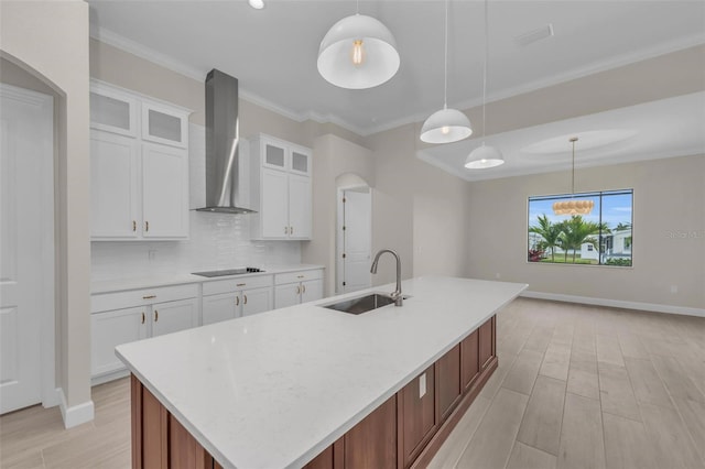 kitchen featuring pendant lighting, white cabinetry, sink, and wall chimney range hood