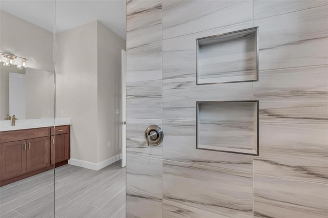 bathroom featuring tiled shower and vanity