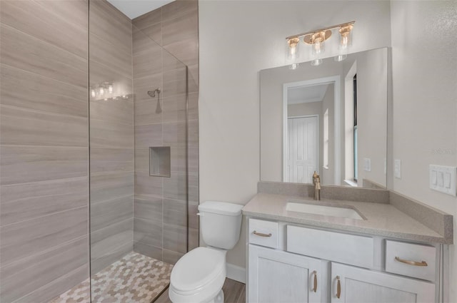 bathroom with vanity, tiled shower, and toilet