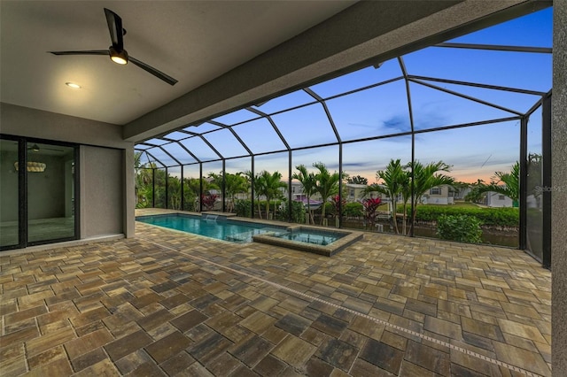 pool at dusk featuring an in ground hot tub, a lanai, and a patio area