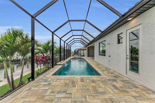 view of pool featuring a patio, an in ground hot tub, a water view, and glass enclosure