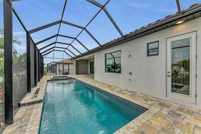 view of swimming pool featuring an in ground hot tub, a patio, and glass enclosure