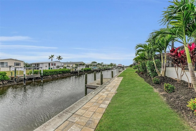 view of dock with a water view and a lawn