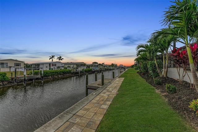 view of dock with a lawn and a water view