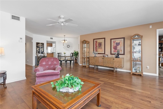 living room with ceiling fan with notable chandelier and hardwood / wood-style flooring