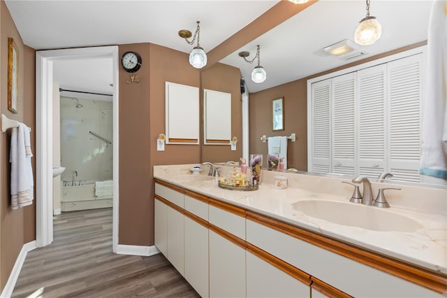 bathroom with hardwood / wood-style floors, walk in shower, and vanity