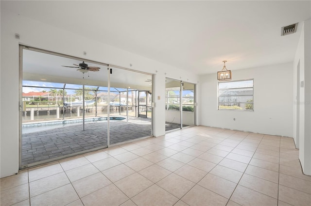 unfurnished room featuring ceiling fan with notable chandelier, a water view, and light tile patterned flooring