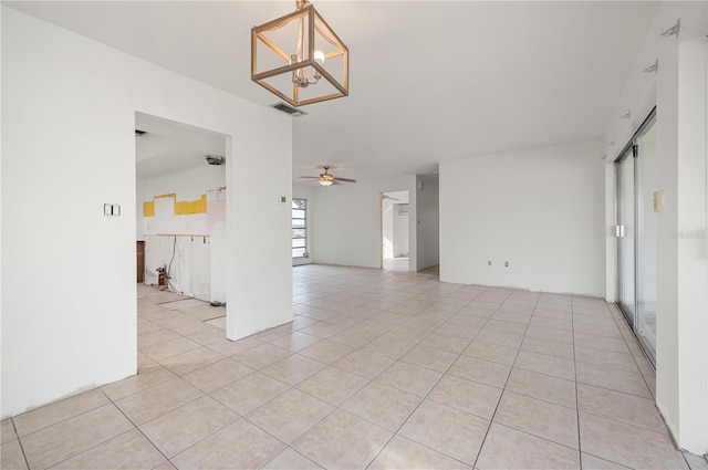 unfurnished room featuring ceiling fan with notable chandelier and light tile patterned floors