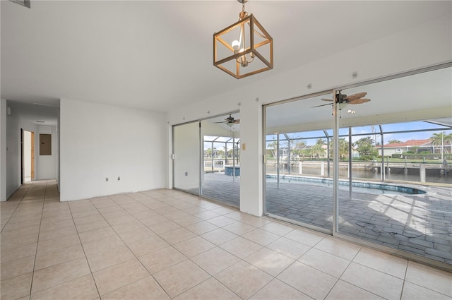 tiled spare room featuring plenty of natural light, electric panel, a water view, and an inviting chandelier