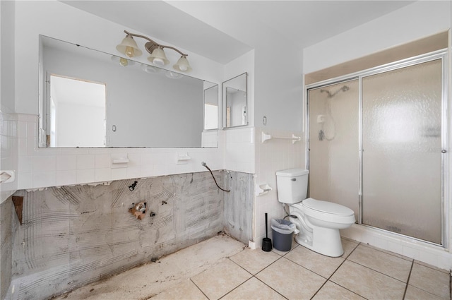 bathroom featuring a shower with shower door, tile walls, tile patterned floors, and toilet