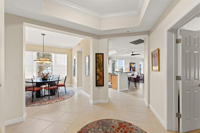 tiled foyer with a tray ceiling and crown molding