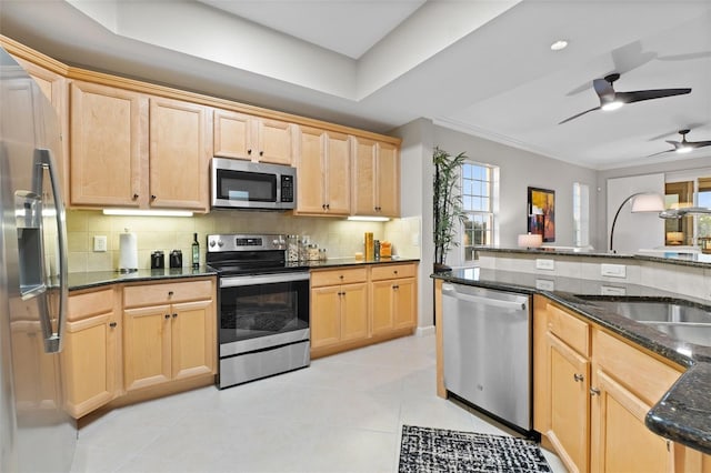 kitchen with light brown cabinetry, backsplash, stainless steel appliances, and dark stone counters