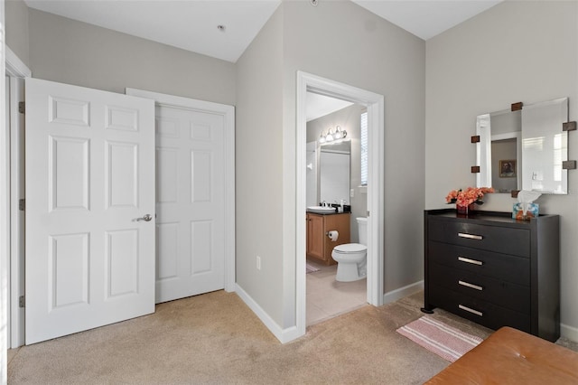 carpeted bedroom featuring sink and ensuite bathroom