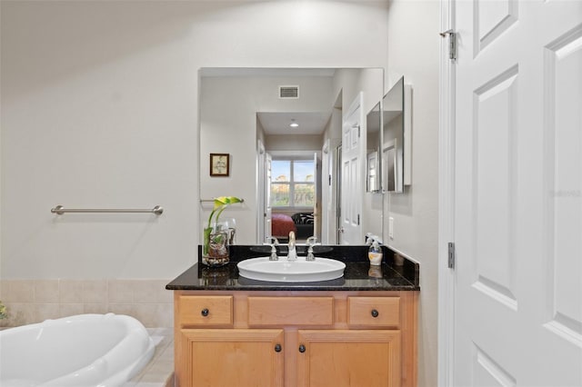 bathroom featuring tiled tub and vanity