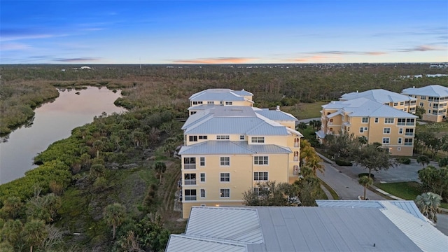 aerial view at dusk featuring a water view