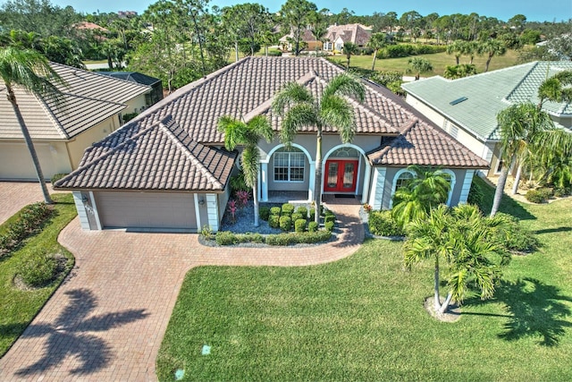 mediterranean / spanish house featuring a front lawn, french doors, and a garage