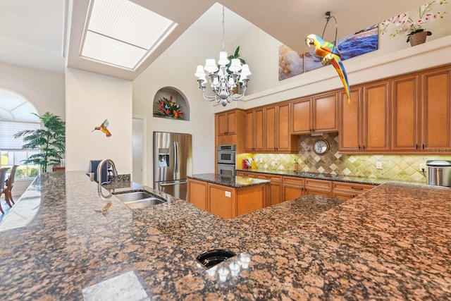 kitchen featuring appliances with stainless steel finishes, dark stone counters, sink, backsplash, and high vaulted ceiling