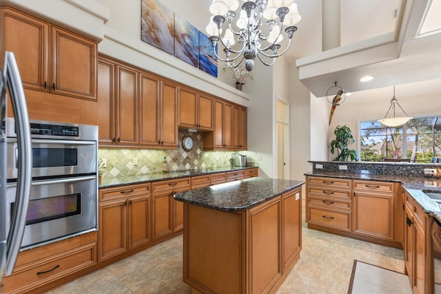 kitchen featuring hanging light fixtures, dark stone counters, a high ceiling, and a chandelier