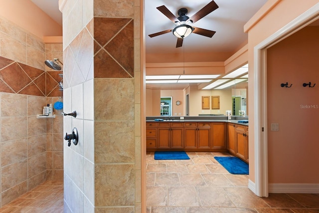 bathroom with ceiling fan, vanity, and tiled shower