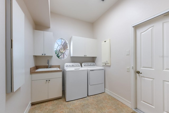 clothes washing area with cabinets, washer and clothes dryer, and sink