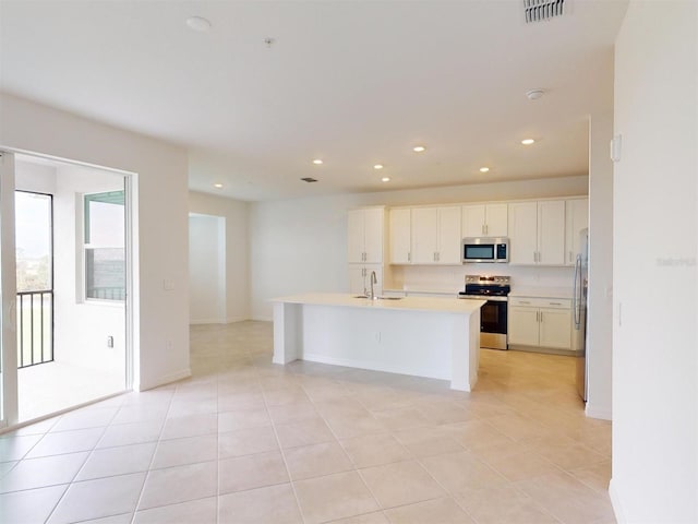 kitchen with sink, light tile patterned flooring, an island with sink, stainless steel appliances, and white cabinets