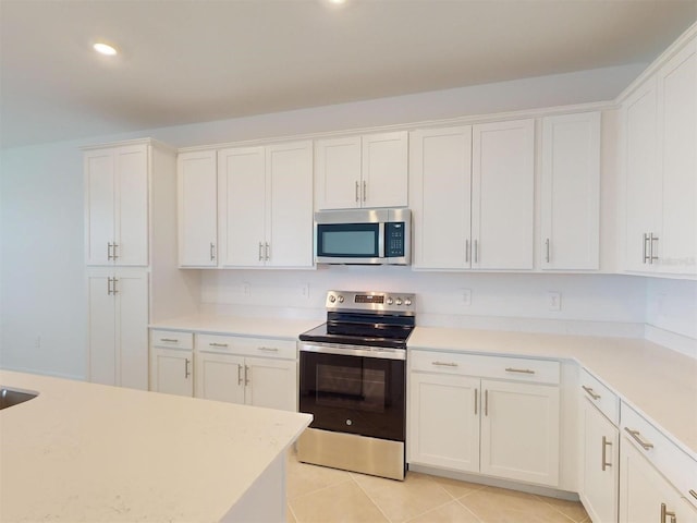 kitchen featuring light tile patterned floors, appliances with stainless steel finishes, and white cabinetry