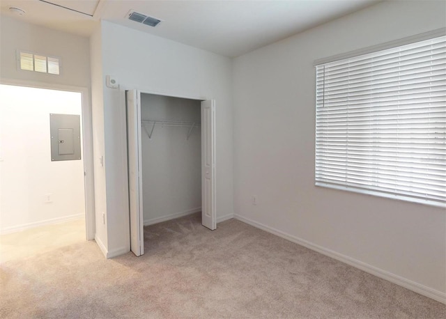 unfurnished bedroom with electric panel, a closet, and light carpet