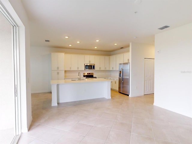 kitchen with white cabinetry, stainless steel appliances, an island with sink, sink, and light tile patterned floors