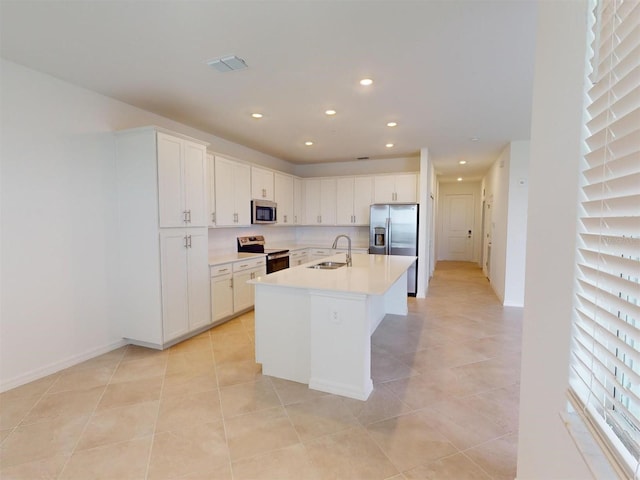 kitchen featuring light tile patterned floors, an island with sink, stainless steel appliances, white cabinets, and sink