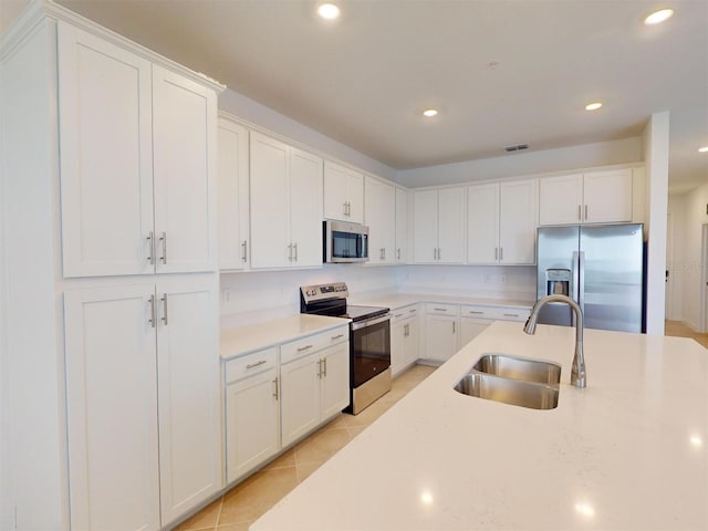 kitchen with light tile patterned floors, sink, white cabinets, and stainless steel appliances