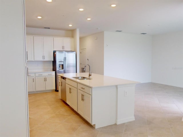 kitchen featuring sink, light tile patterned flooring, appliances with stainless steel finishes, an island with sink, and white cabinets