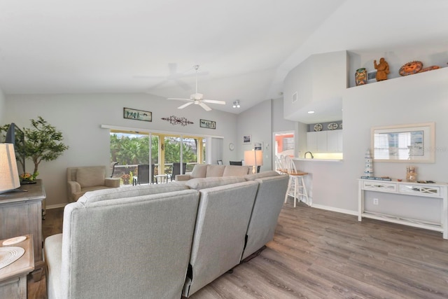 living room with ceiling fan, vaulted ceiling, and hardwood / wood-style flooring