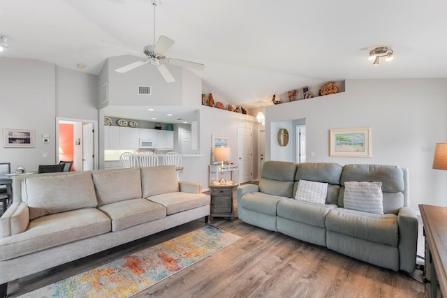 living room featuring ceiling fan, high vaulted ceiling, and light wood-type flooring