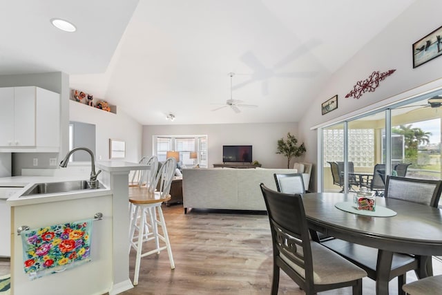 dining space featuring light wood-type flooring, a wealth of natural light, vaulted ceiling, and sink