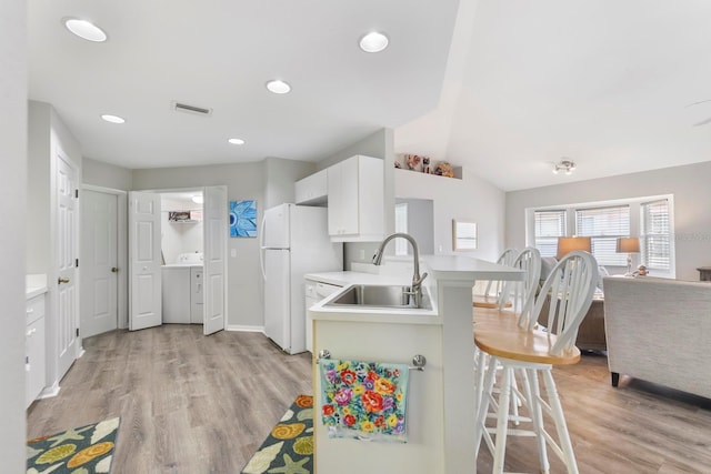 kitchen featuring vaulted ceiling, kitchen peninsula, sink, a kitchen breakfast bar, and white cabinets