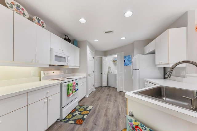 kitchen with light wood-type flooring, white cabinetry, sink, and white appliances