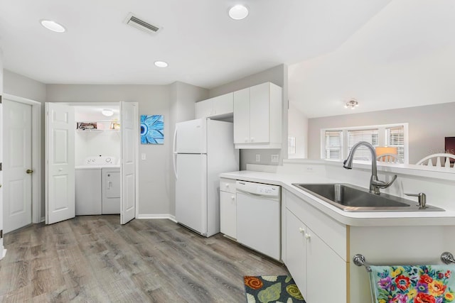 kitchen with kitchen peninsula, white appliances, separate washer and dryer, white cabinets, and sink