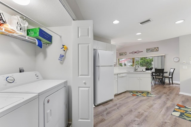 clothes washing area with washer and clothes dryer, light wood-type flooring, and sink