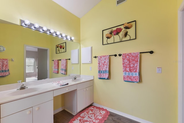 bathroom with wood-type flooring, vanity, and vaulted ceiling