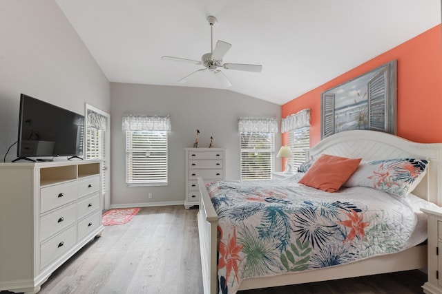 bedroom featuring ceiling fan, multiple windows, light hardwood / wood-style flooring, and lofted ceiling