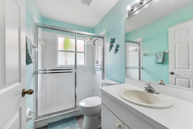 bathroom with toilet, a shower with shower door, and vanity