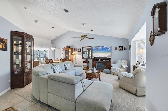 tiled living room with ceiling fan, lofted ceiling, and a textured ceiling