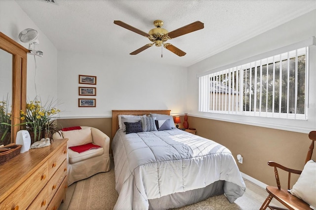 carpeted bedroom featuring ceiling fan and a textured ceiling