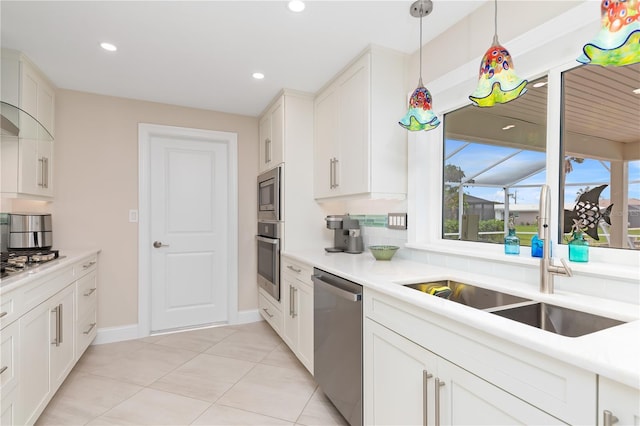 kitchen with pendant lighting, appliances with stainless steel finishes, white cabinetry, sink, and light tile patterned floors