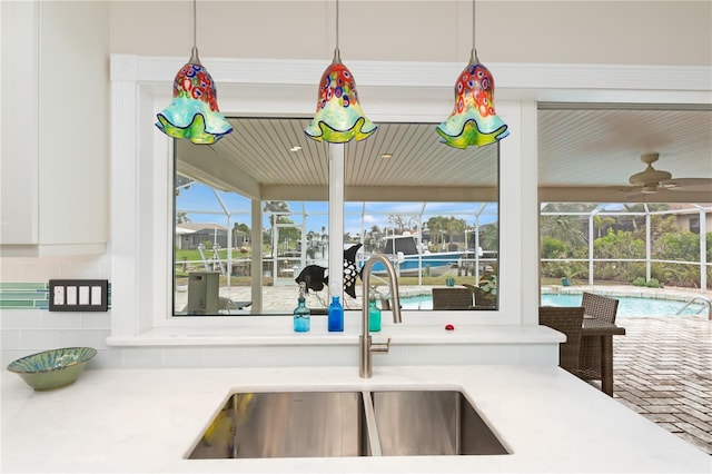 kitchen with white cabinetry, sink, pendant lighting, and ceiling fan