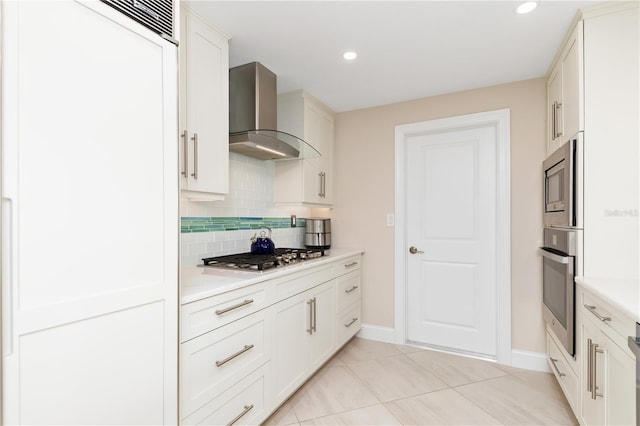 kitchen with white cabinets, appliances with stainless steel finishes, wall chimney exhaust hood, decorative backsplash, and light tile patterned flooring