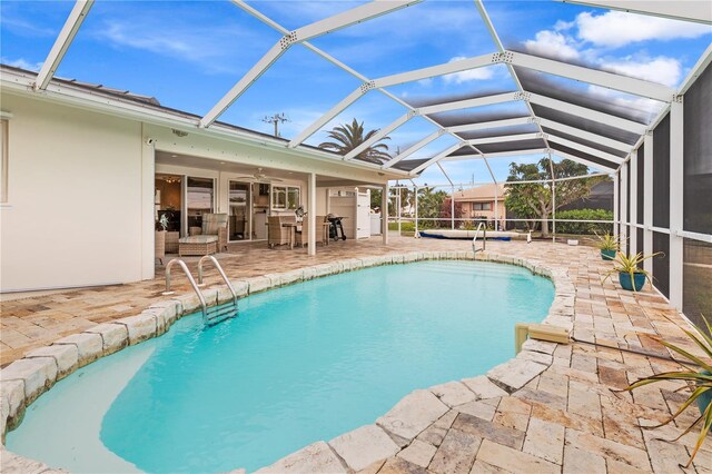 view of pool with ceiling fan, glass enclosure, and a patio