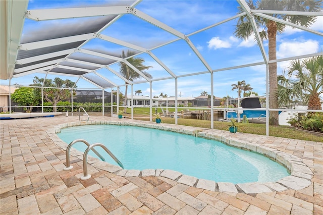 view of pool with a lanai, a water view, and a patio area